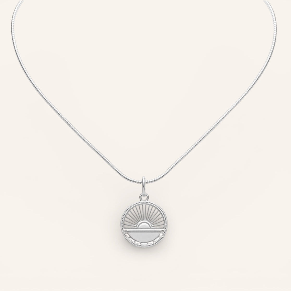 Silver necklace with a round pendant on a white background