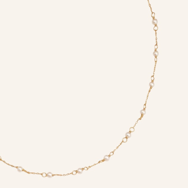 Gold necklace on a light beige background