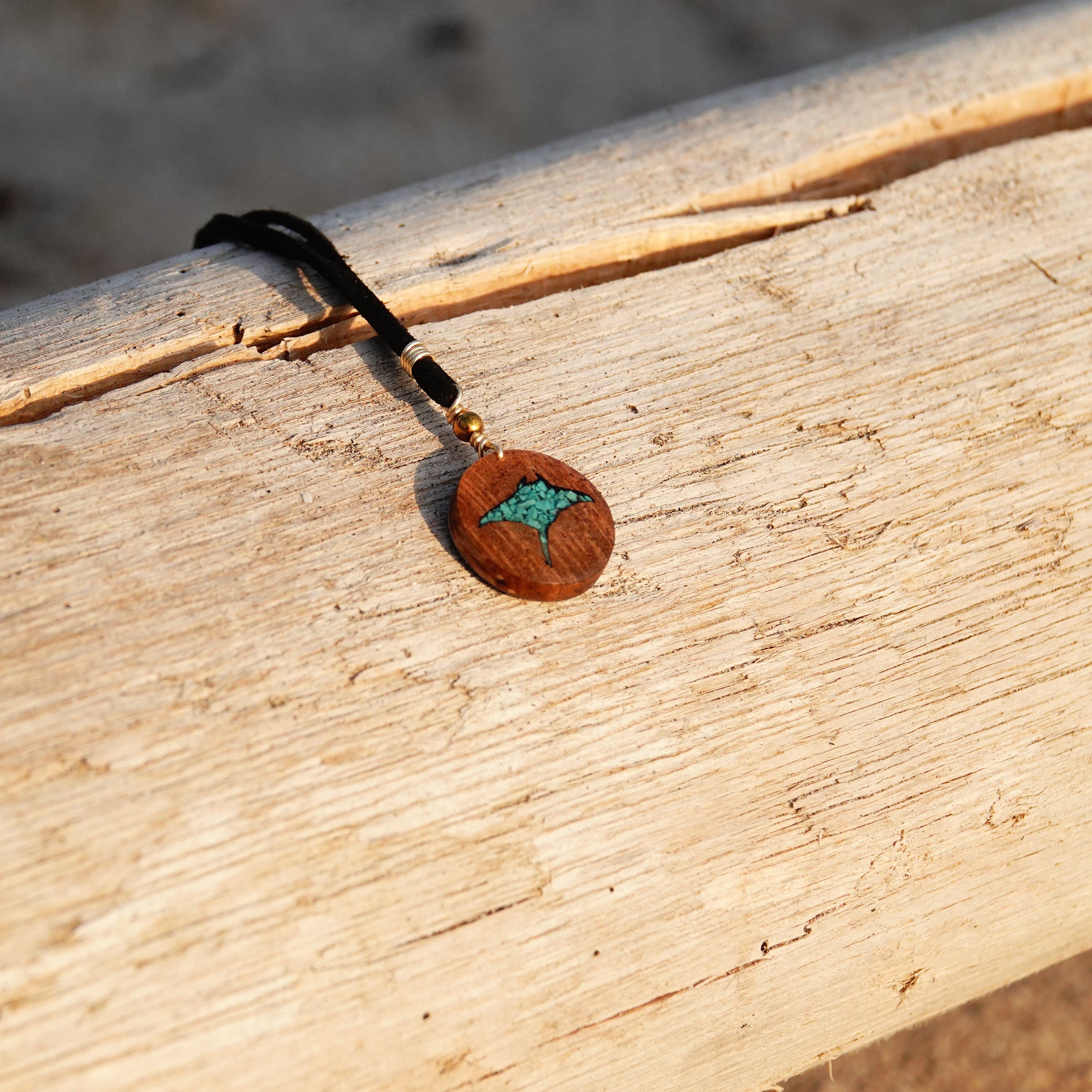 Close-up of a wooden pendant with a manta ray leather necklace