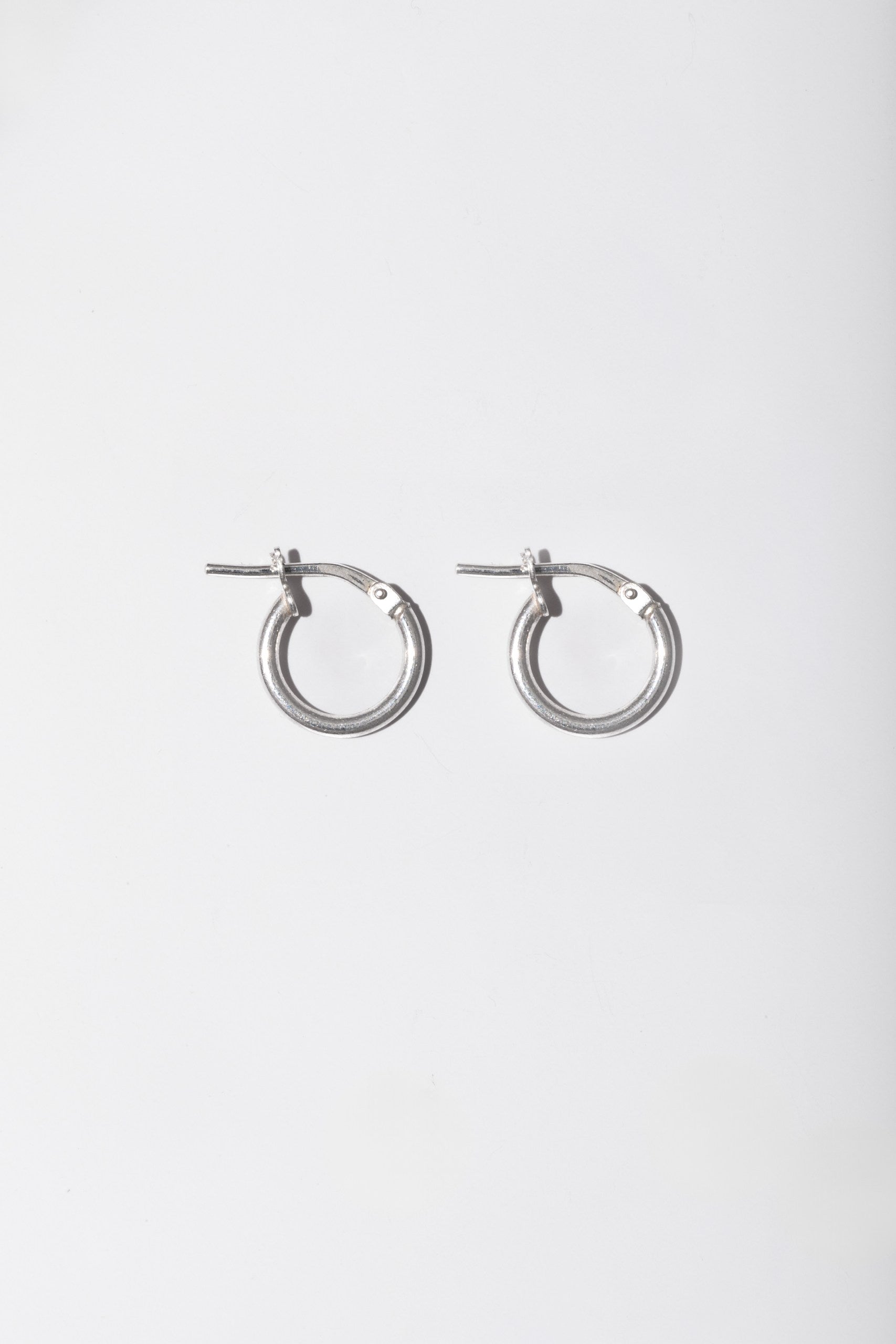 A pair of silver-toned metal hoop earrings with post backs, shown against a plain light gray background.