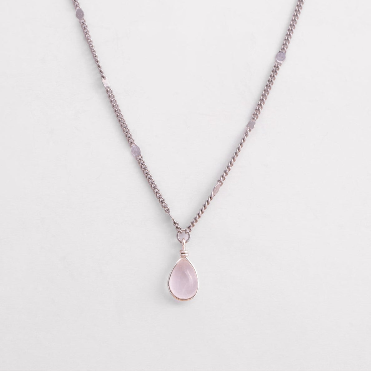 Necklace with a teardrop-shaped pink pendant on a light gray background