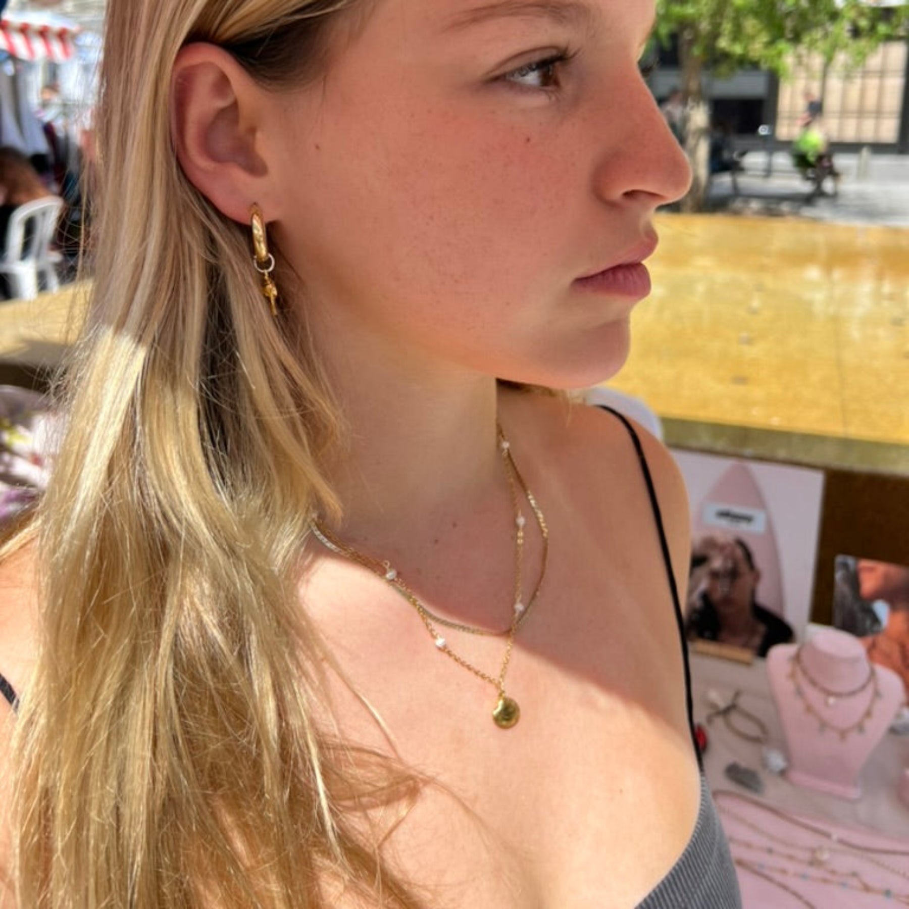 Woman with blonde hair and earrings in an outdoor setting