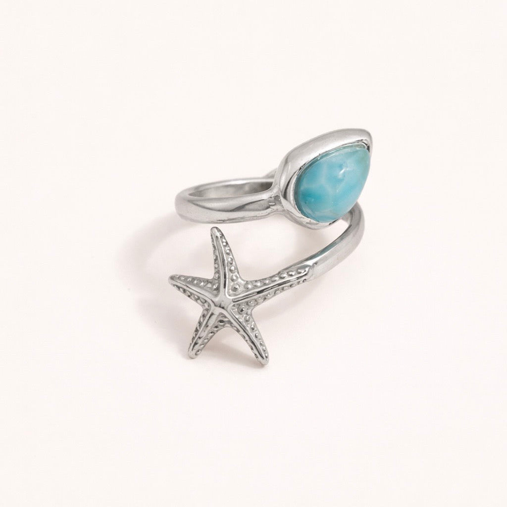 Silver ring with a starfish and blue stone on a white background