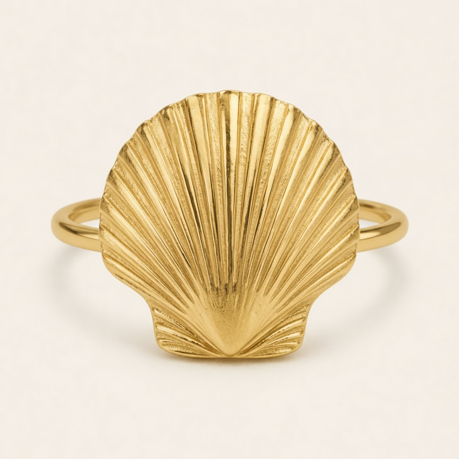 Gold shell-shaped ring on a beige background