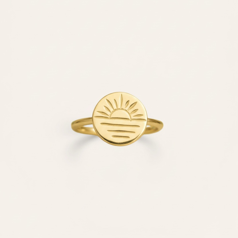Gold ring with a sun design on a white background