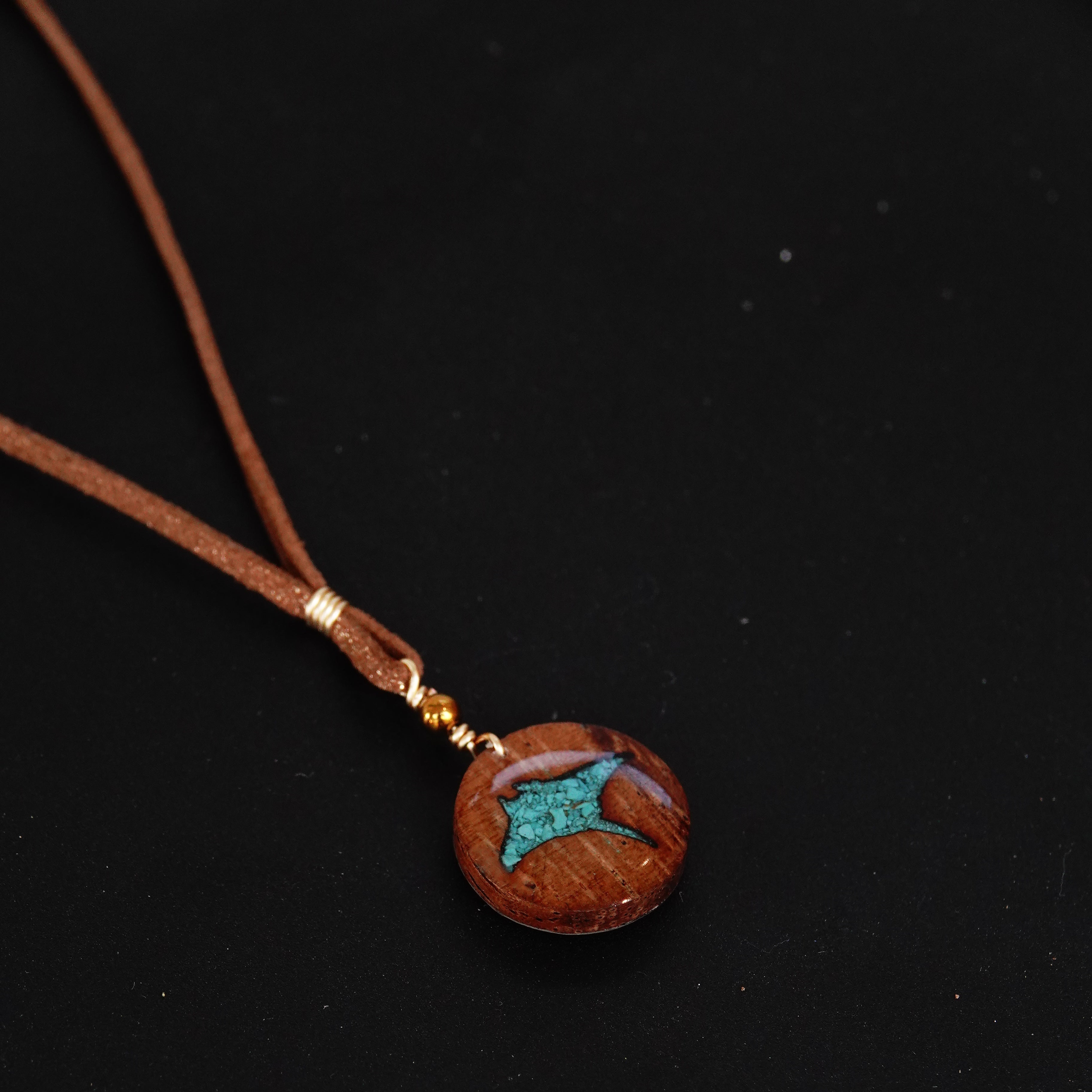 Necklace with a wooden pendant featuring a turquoise stone on a black background