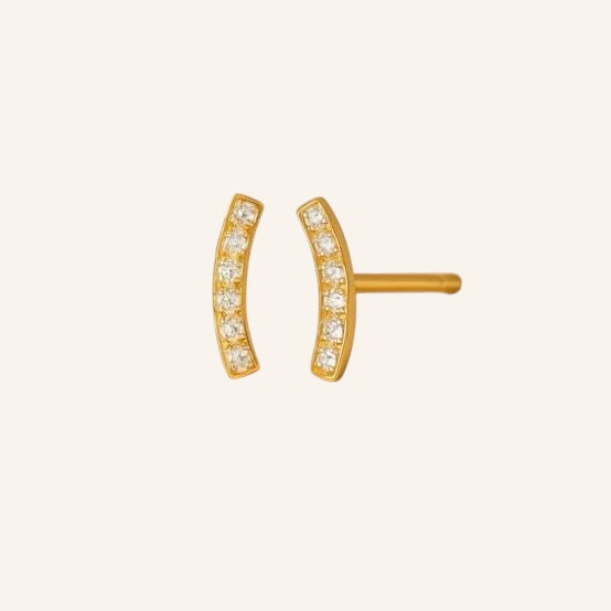 Gold earrings with small diamonds on a light beige background
