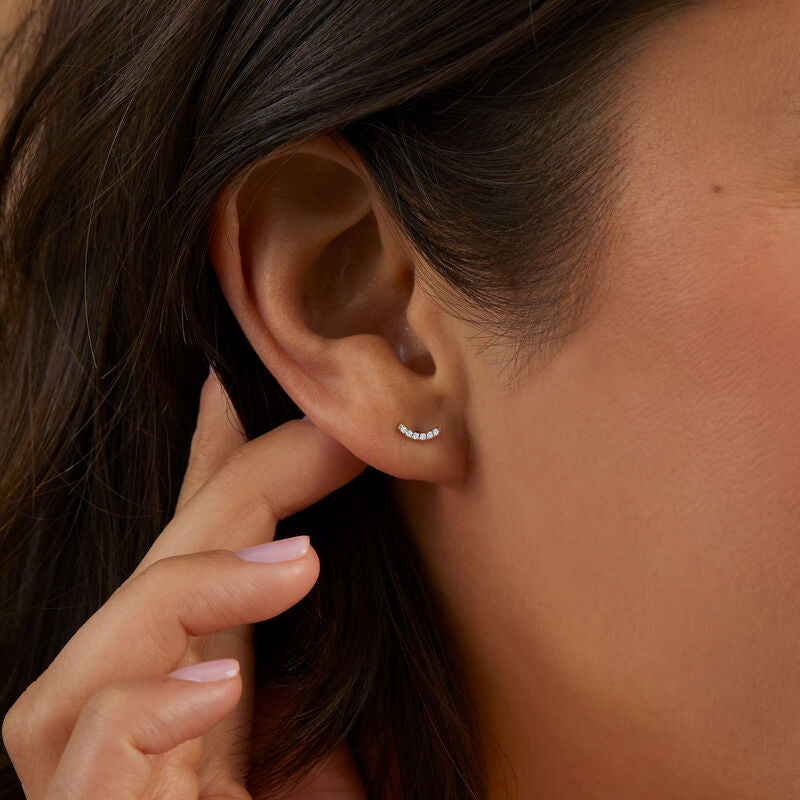 Close-up of an ear with a small earring, hand touching hair