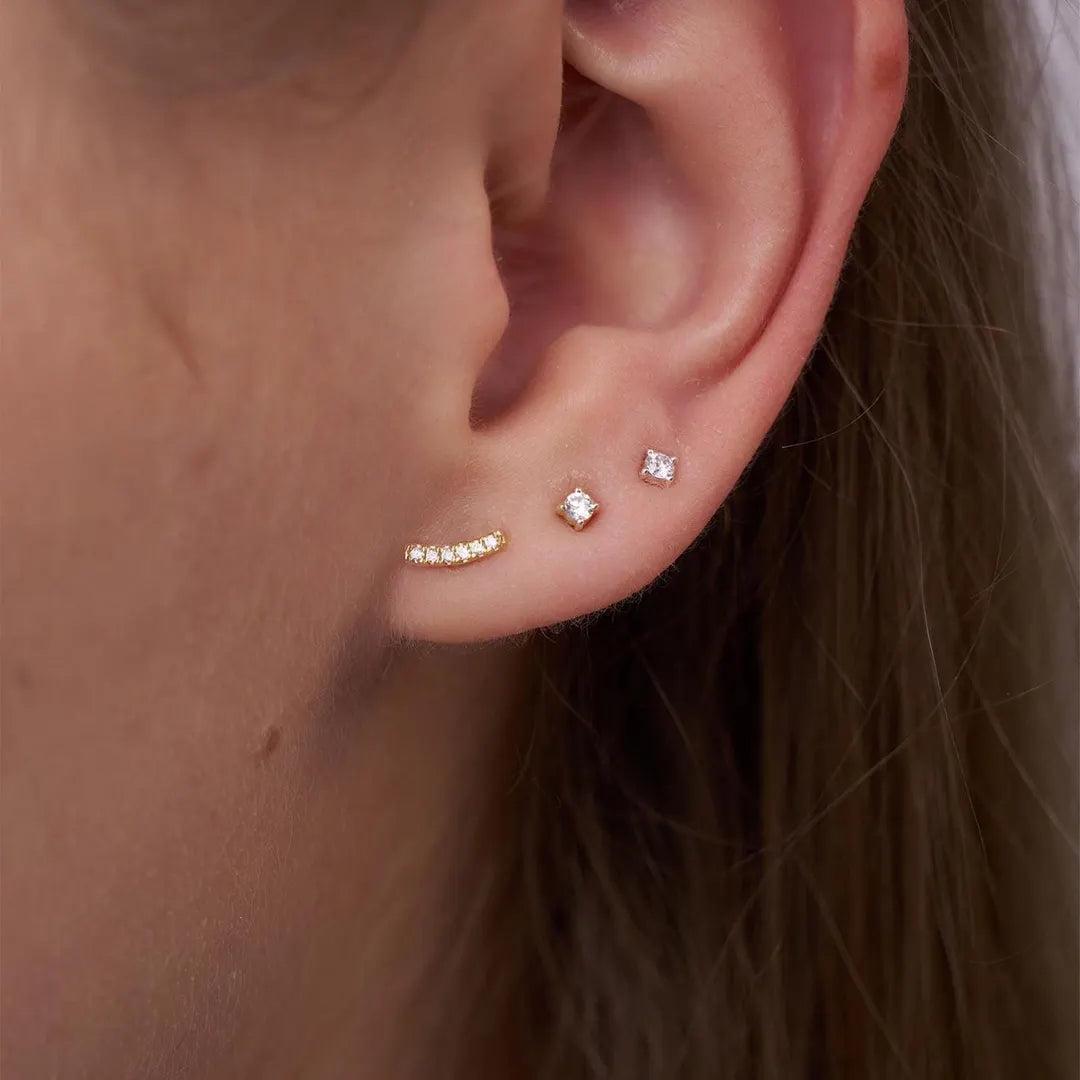 Close-up of an ear wearing gold and diamond stud earrings.
