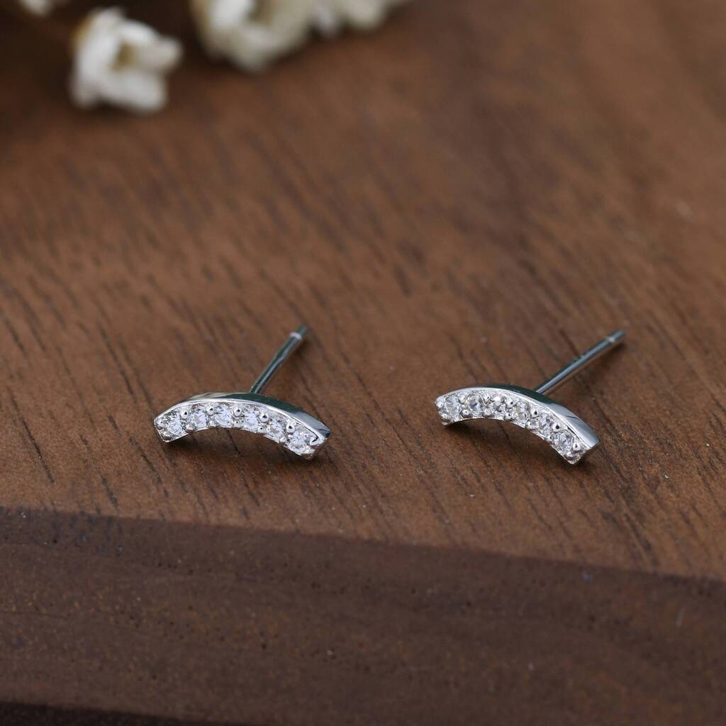 Silver curved earrings with small stones on a wooden surface