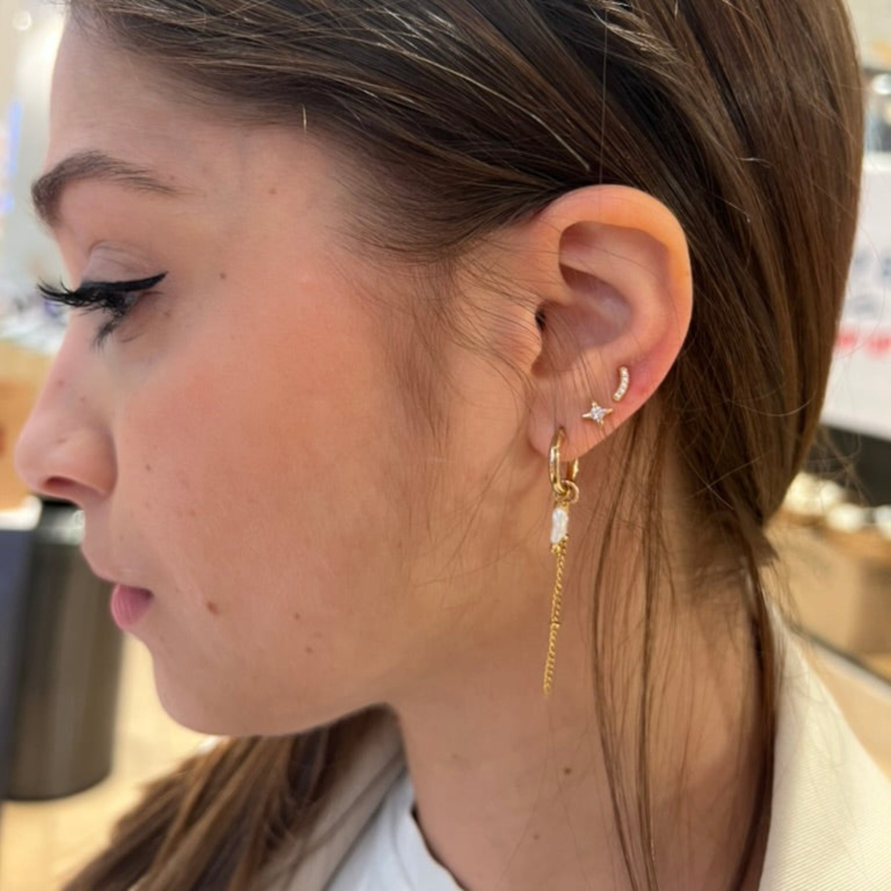 Close-up of a person wearing gold earrings with a blurred background
