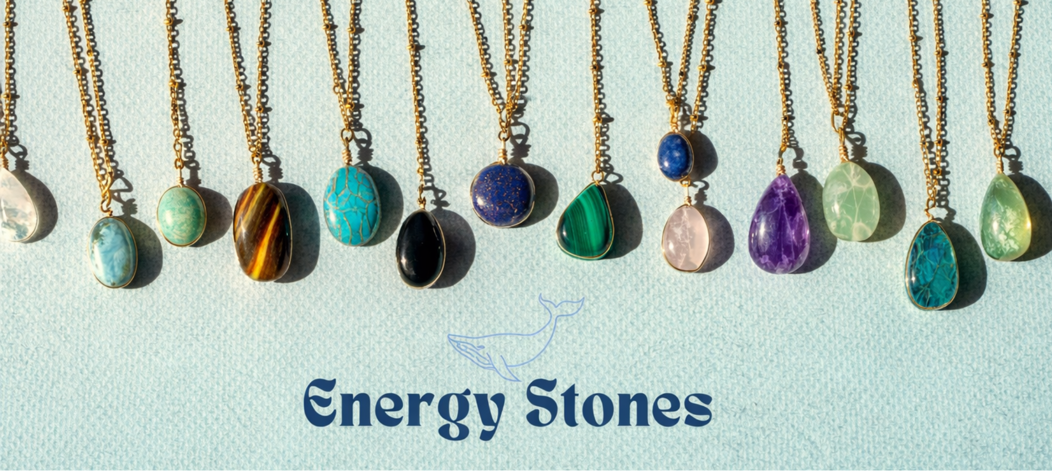 Row of necklaces with various energy stones on a light blue background, featuring the brand 'Energy Stones'.