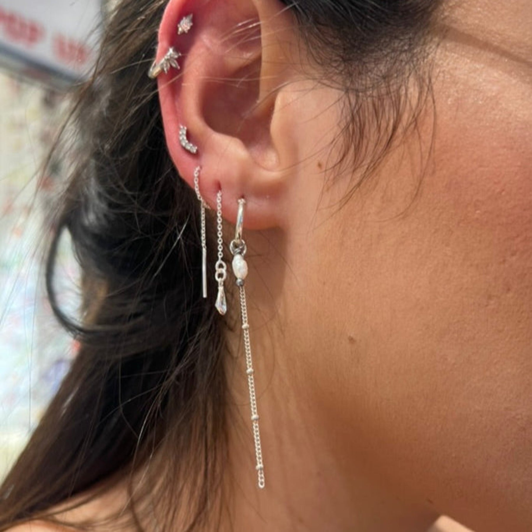 Close-up of an ear with multiple silver earrings