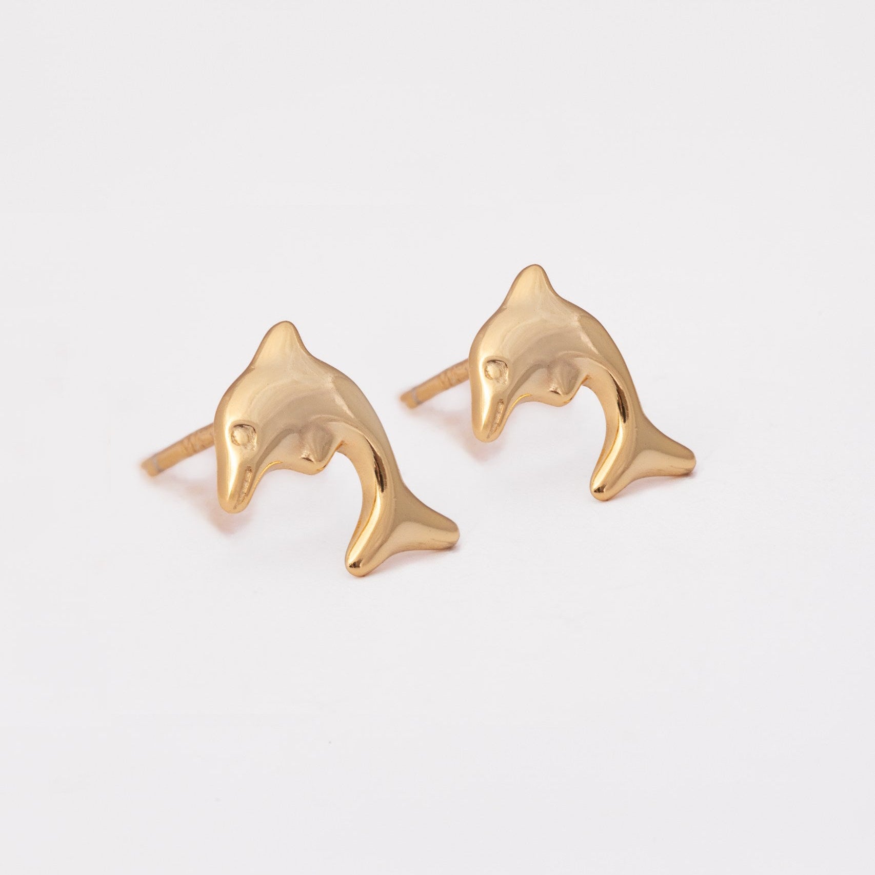Gold dolphin-shaped earrings on a white background