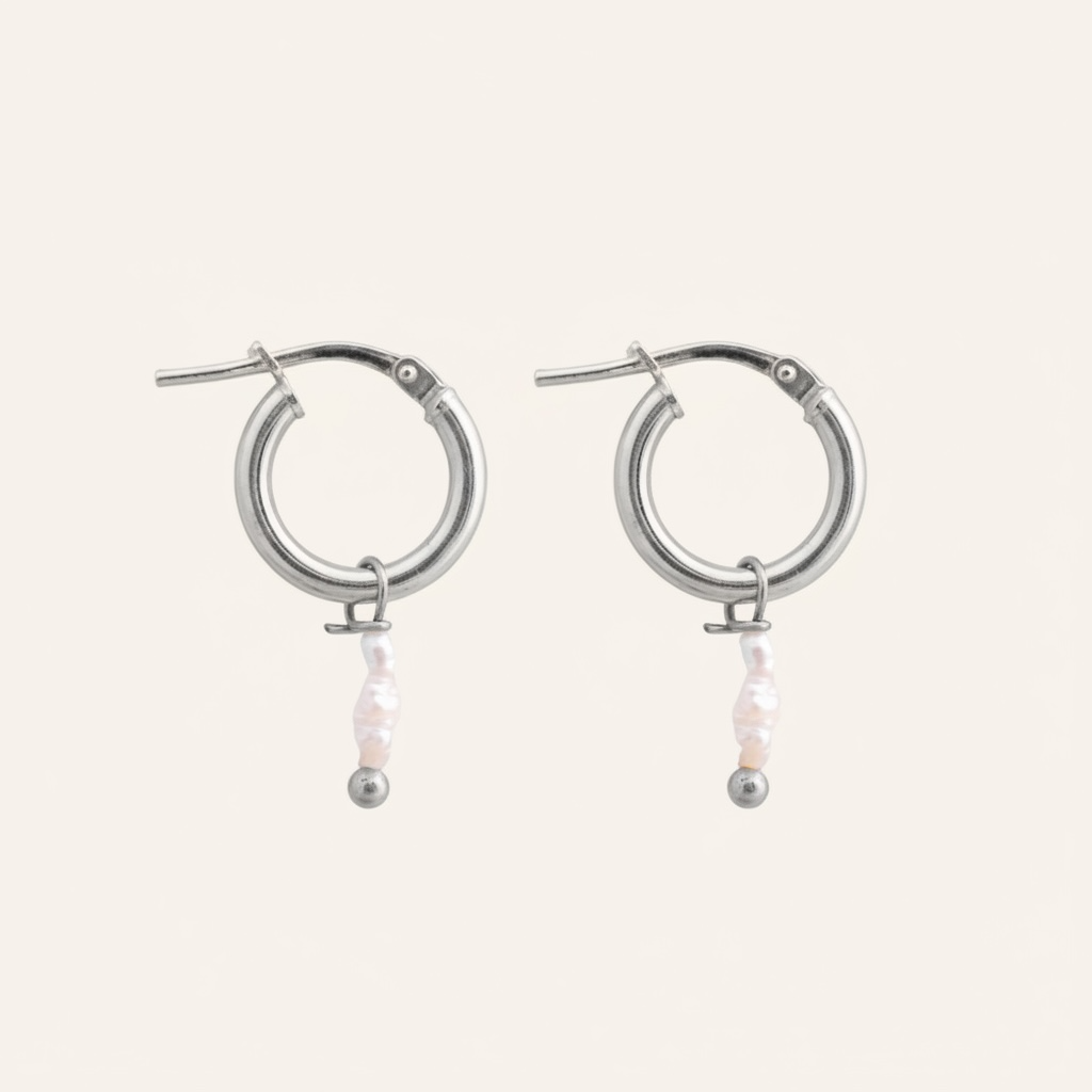 Silver hoop earrings with pearls on a light beige background